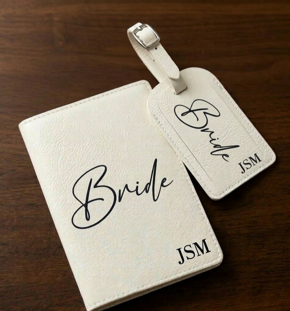 White leather luggage tag and cover with 'Bride' and 'JSM' text on a wooden surface