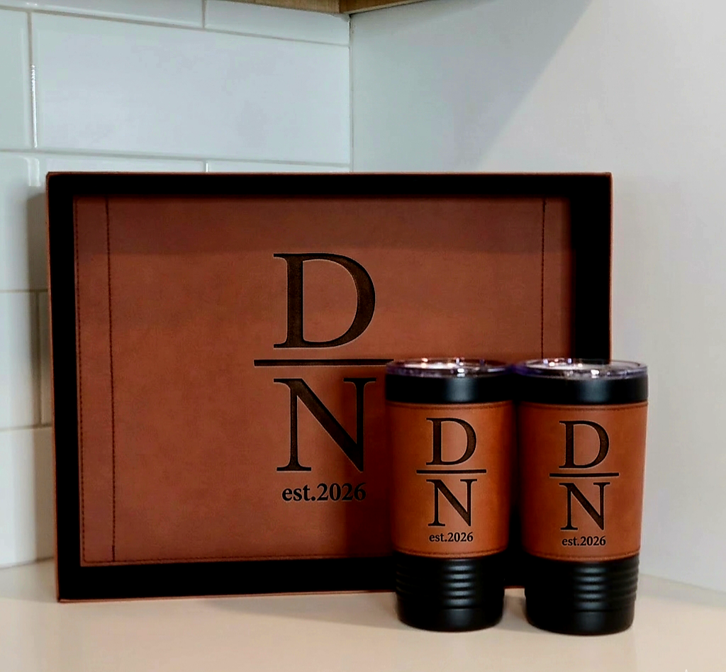 Two brown tumblers with black lids and 'D N est. 2026' text on a matching brown tray.