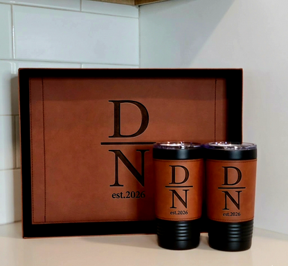 Two brown tumblers with black lids and 'D N est. 2026' text on a matching brown tray.
