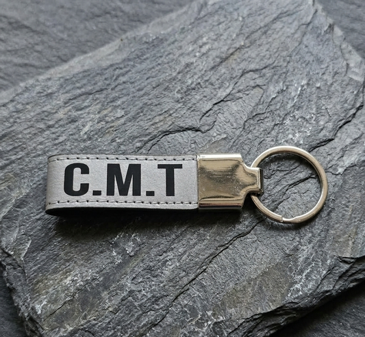 Keychain with 'C.M.T.' text on a stone surface